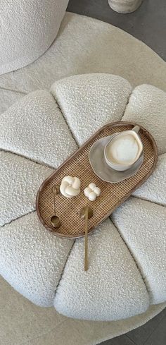 a coffee cup and saucer sitting on top of a white cushioned chair with an ottoman