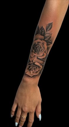 a woman's arm with a rose tattoo on it and her hand holding the wrist