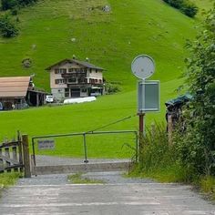 a gate leading to a green hillside with houses in the background