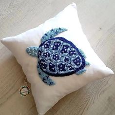 a white pillow with a blue turtle embroidered on it