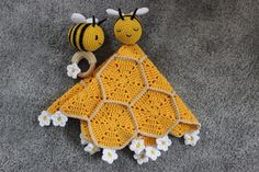 two crocheted bees sitting next to each other on top of a blanket with flowers