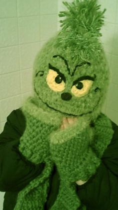 a person wearing a green crocheted sesame character hat and scarf