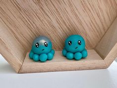 two little blue octopus figurines sitting on top of a wooden shelf next to each other