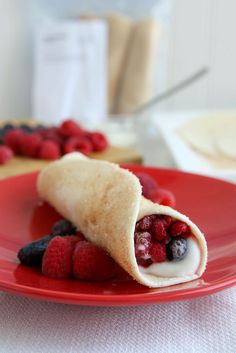 a red plate topped with a pastry filled with berries