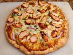 a pizza sitting on top of a cutting board covered in cheese and chicken toppings