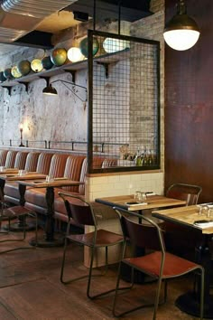 an empty restaurant with tables and chairs in front of a brick wall that has lights hanging from the ceiling