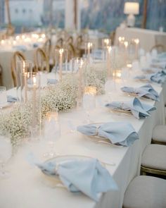 a long table is set with white flowers and candles for an elegant wedding or special event