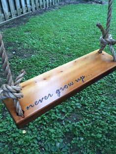 a wooden swing with rope hanging from it's sides and writing on the back