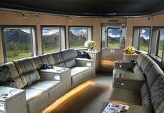 the inside of a train car with couches and luggage on the floor next to windows