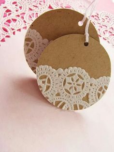 two tags with lace on them are sitting on a doily tablecloth, one is brown and the other is white