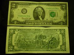 two green dollar bills sitting next to each other