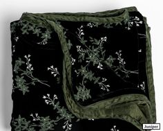 a black and green blanket with white flowers on it