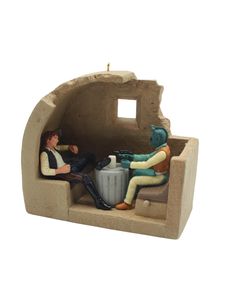 a ceramic figurine of two people sitting in an oven with a coffee pot