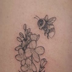 a black and white photo of a bee flying over flowers on the back of a woman's shoulder