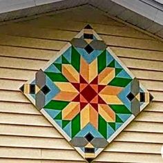 a decorative tile on the side of a house's roof, with an orange and green flower