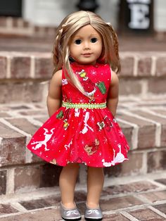 a doll is standing on some steps wearing a red dress with reindeers and snowflakes