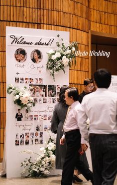 people standing in front of a sign with flowers on it