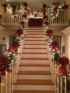 stairs decorated for christmas with lights and garlands on the bannister, along with poinsettis