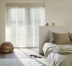 a bedroom with white bedding and wooden blinds