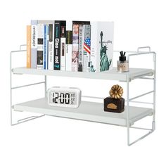 a white shelf with books, alarm clock and other items on it in front of a white background