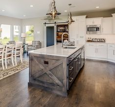 a large kitchen with an island in the middle and lots of white furniture around it