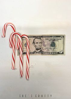 two candy canes are on top of a one dollar bill