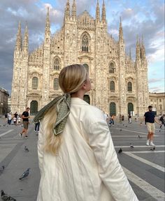 a woman is standing in front of a cathedral