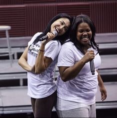 two women standing next to each other with microphones in their hands and one holding a mic