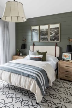 a bedroom with green walls and white bedding, two pictures on the wall above the bed