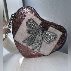 New Kurt Geiger Landon Kensington Bow Glitter Heart Crossbody Bag From Kurt Geiger London, The Kensington Bow Glitter Heart Crossbody Bag Features: 75% Acrylic 25% Polyethylene Terephthalate Exterior Polyester Lining Silver Hardware Single Chain Strap Zipper Closure Center Divider And Slash Pocket Approx.: 7.08'' W X 6.29'' H X 1.96'' D; 20.47'' Strap Drop Heart Crossbody Bag, Pretty Purses, Slash Pocket, Handbag Essentials, Patent Leather Bag, Purple Bag, Phone Ideas, Pink Quilts