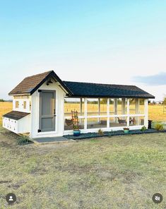 a small white shed sitting on top of a grass covered field