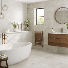 a white bath tub sitting in a bathroom next to a sink under a round mirror