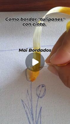 someone is drawing on a piece of paper with a yellow ribbon and some writing in spanish