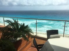 a balcony overlooking the ocean with tables and chairs