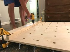 a man is using a drill to attach the base of a bed frame with screwdrivers