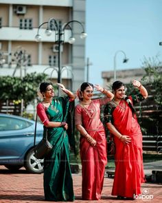 three women in red and green saris posing for the camera