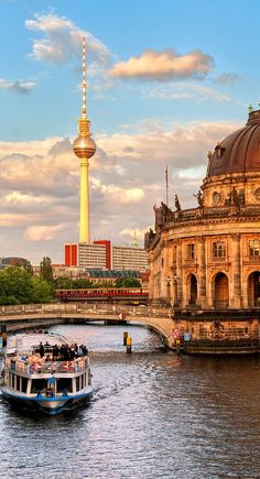 a boat is going down the river in front of a building with a golden spire