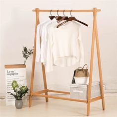 a wooden clothes rack with two shirts hanging on it and a basket next to it