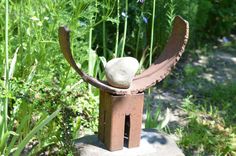 a stone sculpture sitting on top of a cement block in the middle of a garden