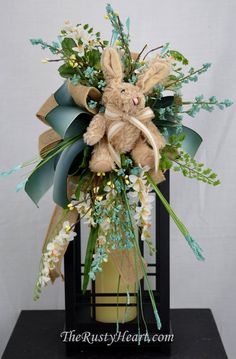 a teddy bear sitting on top of a vase filled with flowers