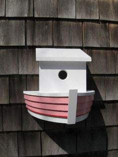 a bird house on the side of a wooden building with a shadow cast by it