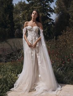 a woman in a wedding dress with a veil on her head and flowers around her shoulders