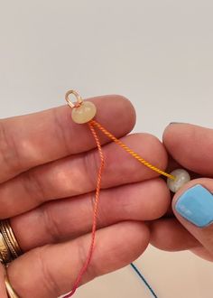 a person is holding some colorful thread in their left hand and there are two beads attached to the string