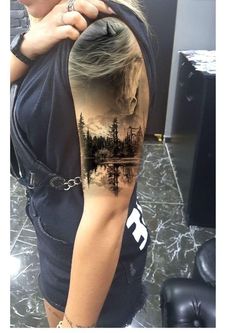 a woman with a tattoo on her arm is looking down at the water and trees