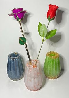 three different colored vases with flowers in them