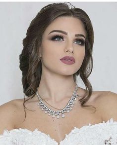 a woman wearing a white dress and necklace with pearls on it's neck, in front of a white background