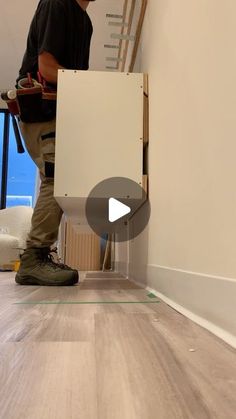 a man standing next to a white board on top of a hard wood floor in an unfinished room