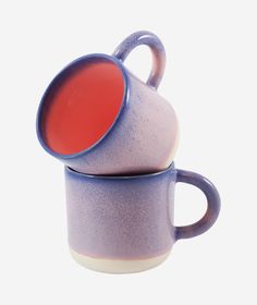 two purple and white coffee mugs stacked on top of each other with red liquid in them