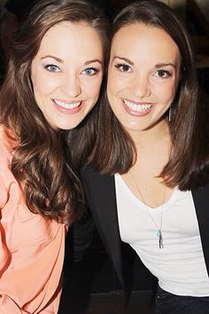 two women sitting next to each other smiling