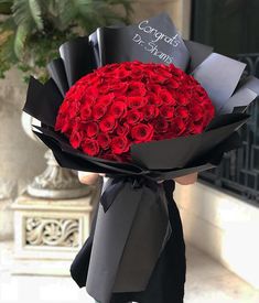 a woman holding a bouquet of red roses